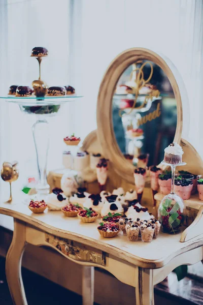 Düğün tatlılar kapaklar ve kek bir ayna restoranda bir altın renkli arka plan üzerinde — Stok fotoğraf