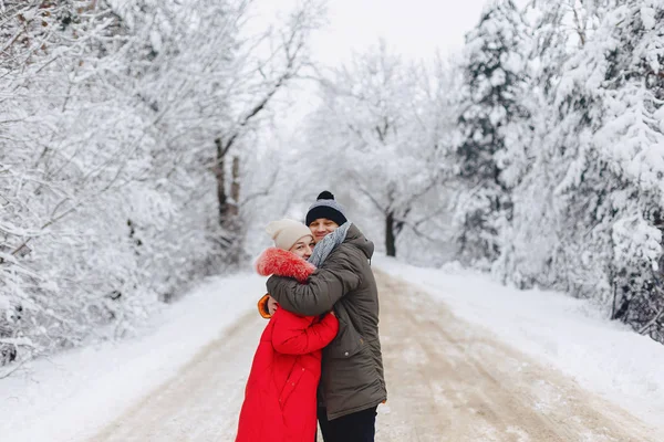 A beautiful family couple walking on a snowy road in the woods — Stock Photo, Image