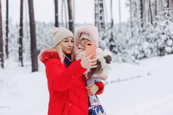 Maman tient le bébé dans ses bras et fait le selfie dans la neige — Photo
