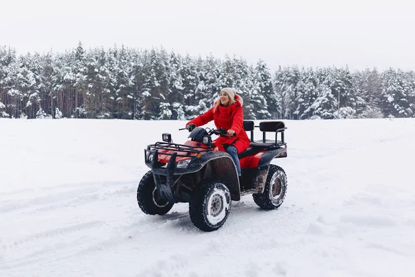 A pretty girl riding a quadrocycle in a picturesque snowy area — Stock Photo, Image