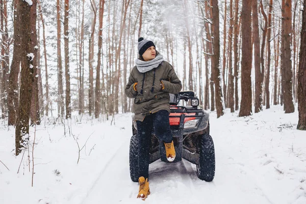 A boy is standing near a quad bike in the middle of the forest — Stock Photo, Image