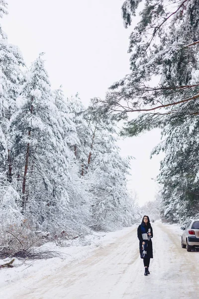 La fille va au milieu d'une route forestière enneigée — Photo