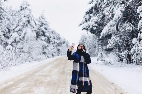 Una bella ragazza fa un selfie nel mezzo di una foresta innevata roa — Foto Stock