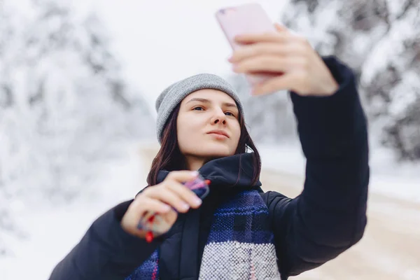 Ein hübsches Mädchen macht ein Selfie inmitten eines verschneiten Waldes — Stockfoto