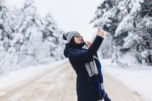 Une jolie fille fait un selfie au milieu d'une forêt enneigée roa — Photo