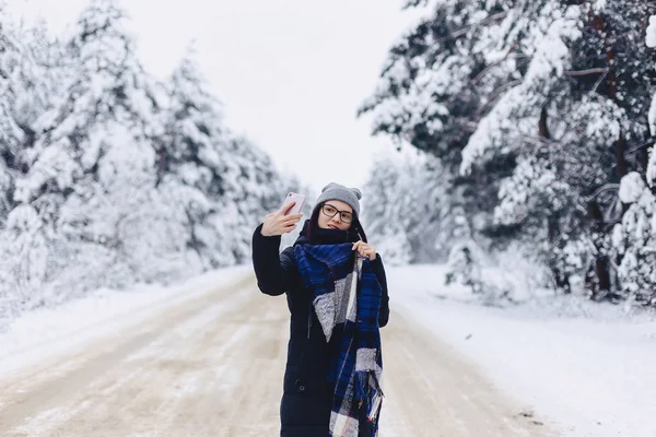 Une jolie fille fait un selfie au milieu d'une forêt enneigée roa — Photo