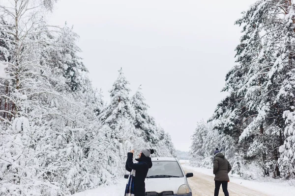 Fille en vêtements d'hiver sur la route de la forêt enneigée ramasse des paysages — Photo