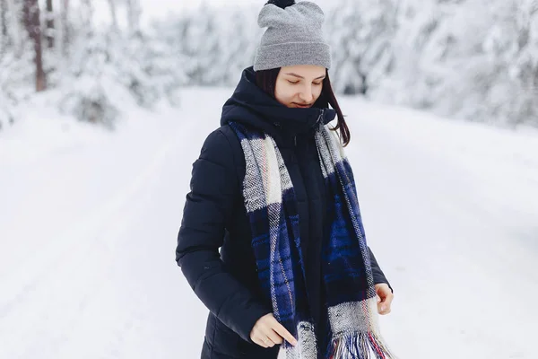 Uma menina usando um chapéu de inverno posa em uma câmera no fundo — Fotografia de Stock