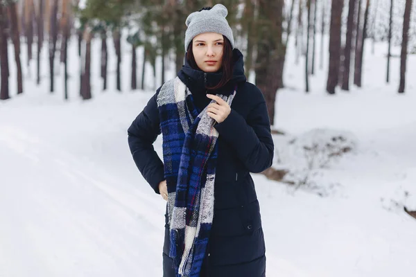 Uma menina usando um chapéu de inverno posa em uma câmera no fundo — Fotografia de Stock