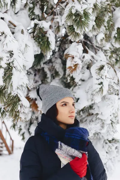 Retrato de uma menina de pé sob um pinheiro coberto de neve — Fotografia de Stock