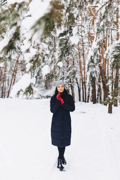 女孩走在白雪覆盖的森林中的松树在红色 g — 图库照片