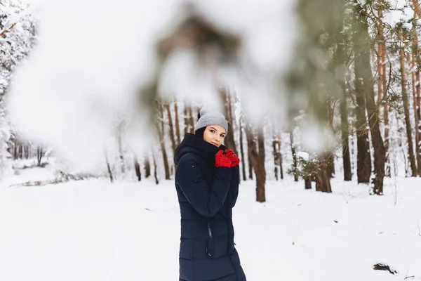Fata merge într-o pădure acoperită de zăpadă printre pini în roșu g — Fotografie, imagine de stoc