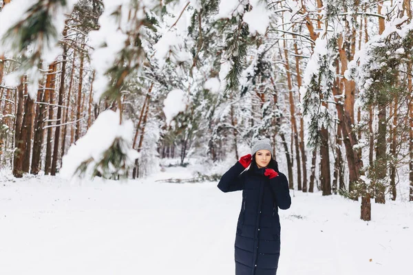 La fille se promène dans une forêt enneigée parmi les pins en rouge g — Photo