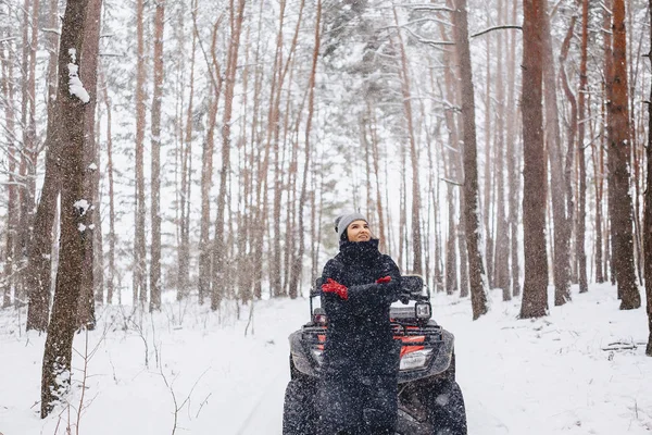 Jovem em um passeio de moto na floresta de pinheiros cobertos de neve em — Fotografia de Stock