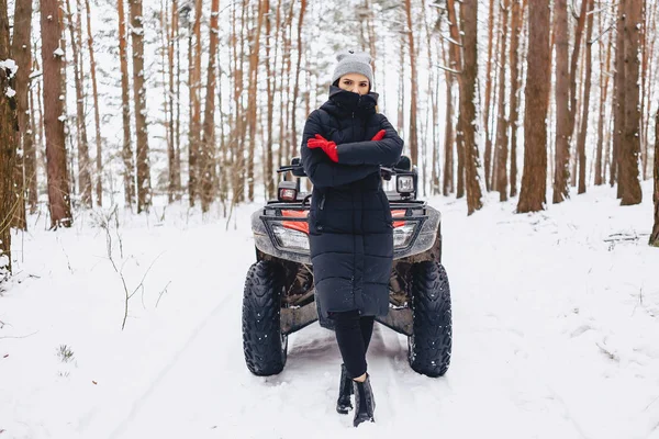 Jong meisje op een motorfiets rijdt in sneeuw bedekte dennenbos in — Stockfoto