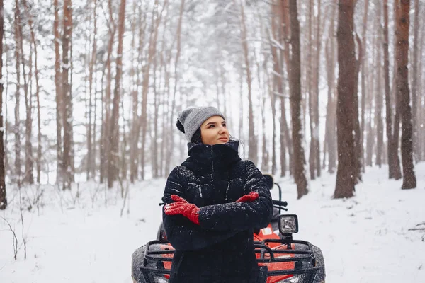 骑摩托车的年轻女孩在积雪覆盖的松树林 — 图库照片