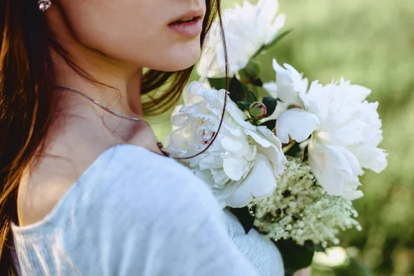 La chica camina con flores en un campo en una bicicleta en la parte posterior — Foto de Stock