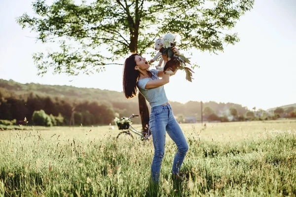 Das Mädchen geht mit einem Welpen auf einem Feld in einem Fahrrad auf dem Rücken — Stockfoto