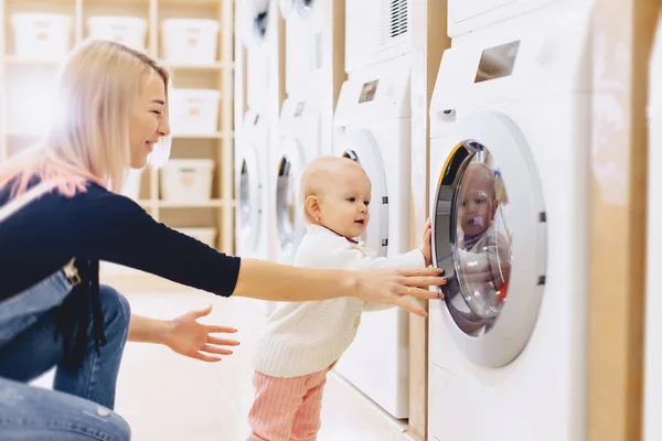 Mama i dziecko w pralni rzeczy i grać — Zdjęcie stockowe