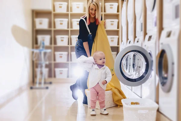 En kvinna med ett barn sätter arken i tvätten — Stockfoto