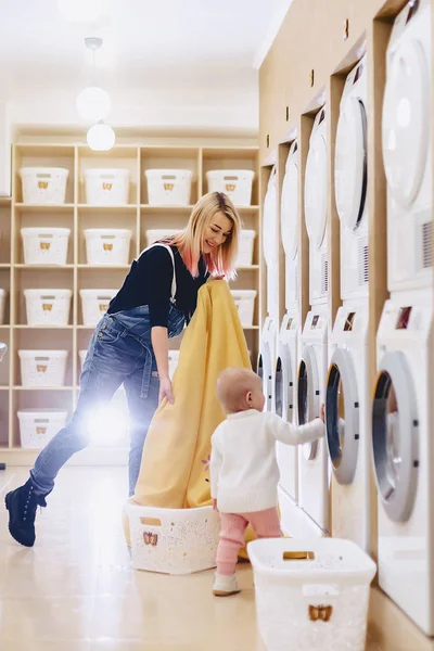 A woman with a child puts the sheets in the laundry — Stock Photo, Image