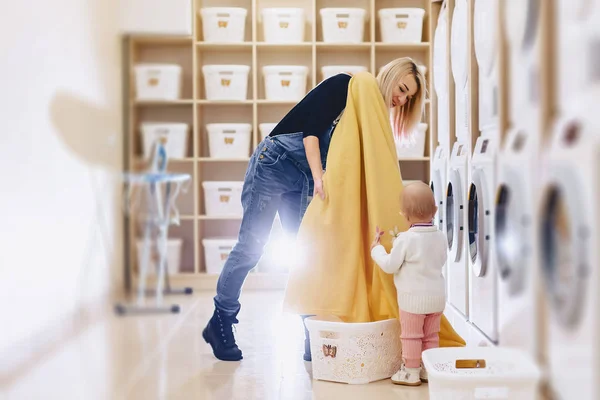 En kvinna med ett barn sätter arken i tvätten — Stockfoto