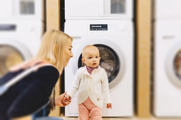 Kvinna med baby nära tvättmaskin — Stockfoto