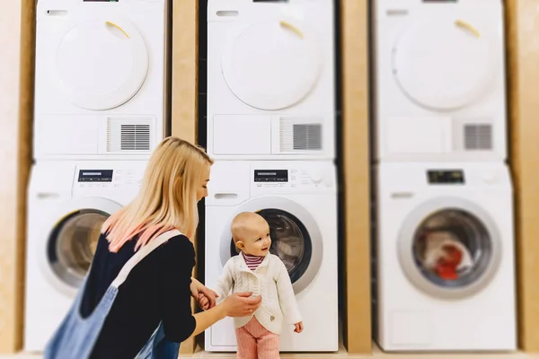Kvinna med baby nära tvättmaskin — Stockfoto