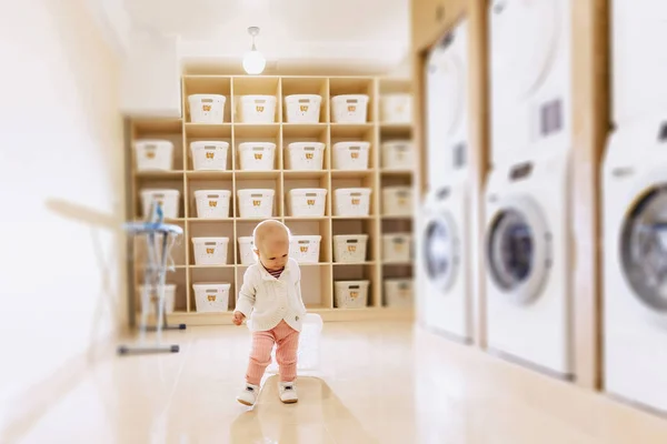 O bebê está andando na lavanderia no fundo dela — Fotografia de Stock