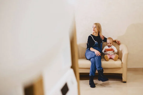 A woman with a child is sitting on the sofa in the laundry in th — Stock Photo, Image