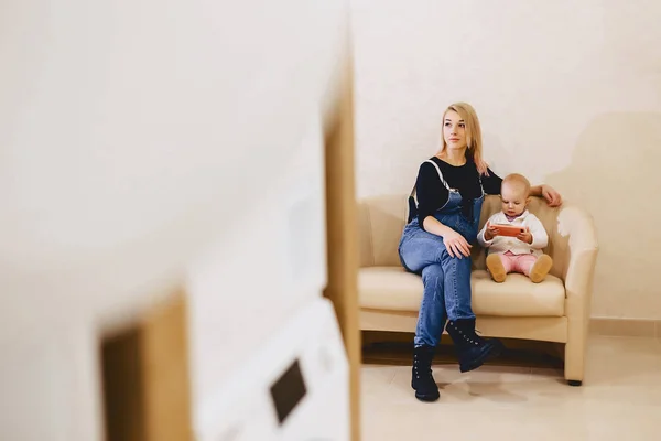 Žena s dítětem a sedí na pohovce v prádelně v th — Stock fotografie