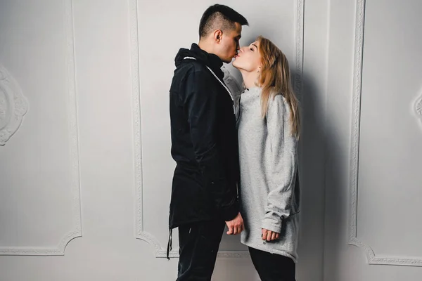 Pareja joven abrazándose y posando sobre un fondo claro — Foto de Stock