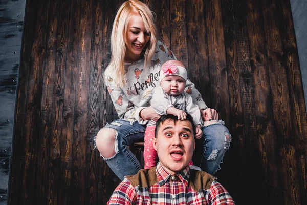 Madre y padre con su bebé en una silla de bar contra el bac — Foto de Stock