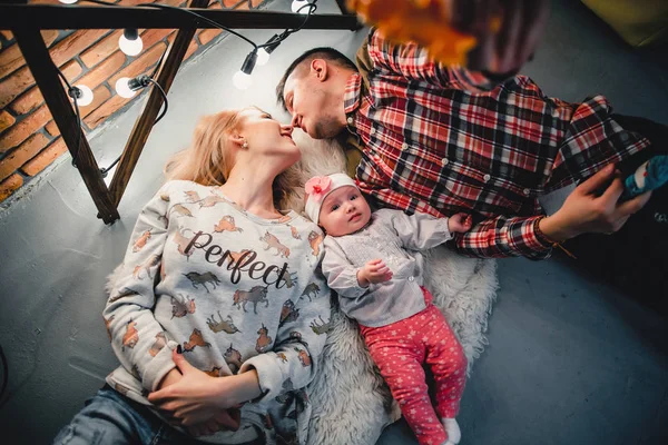 Mama, Papa und Baby liegen auf einem Wollteppich und lächeln — Stockfoto