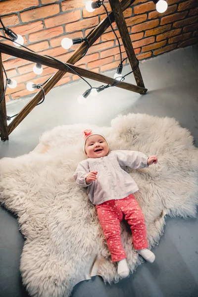 A criança está deitada em um tapete de lã e sorri para a câmera — Fotografia de Stock