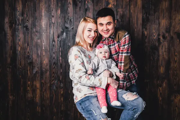 Madre y padre con su bebé en una silla de bar contra el bac — Foto de Stock