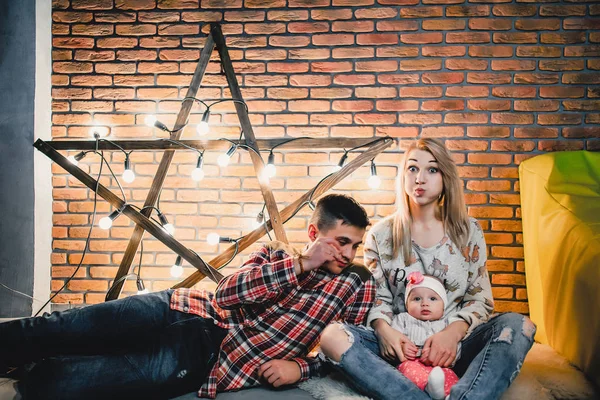 Eltern mit ihrem Kind auf dem Hintergrund eines Sterns mit Glühbirnen — Stockfoto