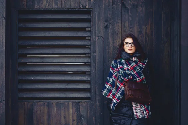 Красива дівчина в окулярах і шарф на дерев'яній стіні — стокове фото