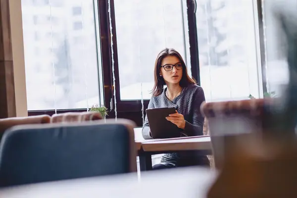 A pretty girl in glasses works on a coffee table