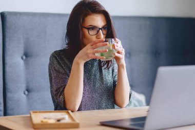 genç güzel kız bir laptop için limonlu sıcak çay içme