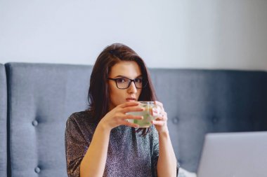 genç güzel kız bir laptop için limonlu sıcak çay içme