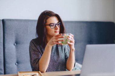 genç güzel kız bir laptop için limonlu sıcak çay içme