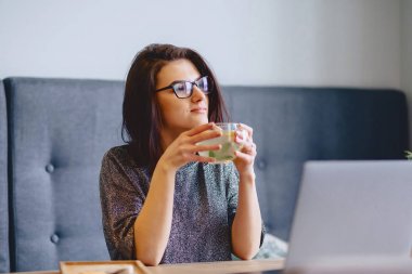 genç güzel kız bir laptop için limonlu sıcak çay içme