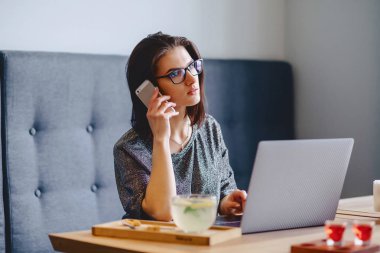 güzel bir kız bardaklarda bir laptop bir CA için telefonla konuşuyor