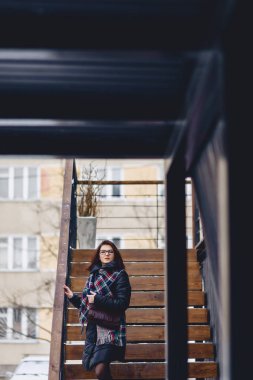 Ahşap merdiven gözlük kışın giyen bir kız giyiyor