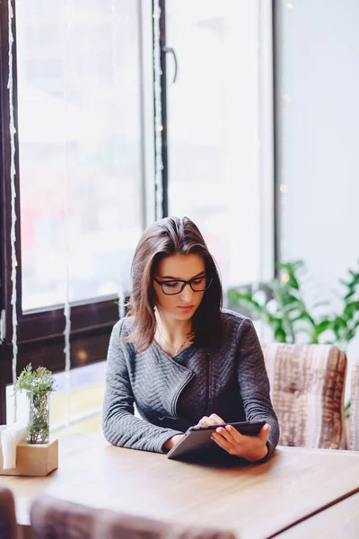 A pretty girl in glasses works on a coffee table