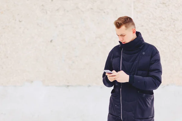 Guy in winter jacket writes sms — Stock Photo, Image