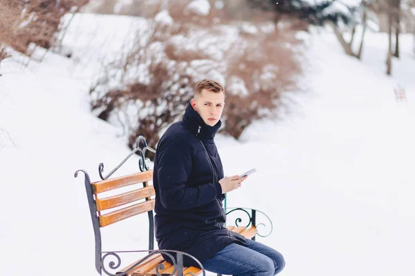 Boy in a winter jacket on a bench wrote sms — Stock Photo, Image