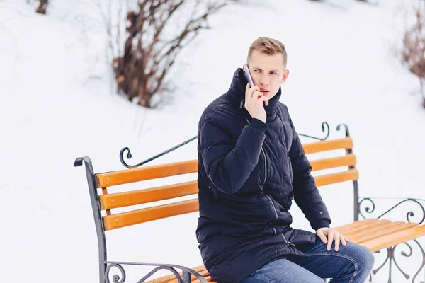 Killen i vinter jackan talar i telefon på gatan — Stockfoto