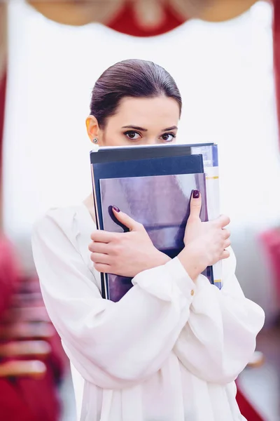 girl hides her face behind documents